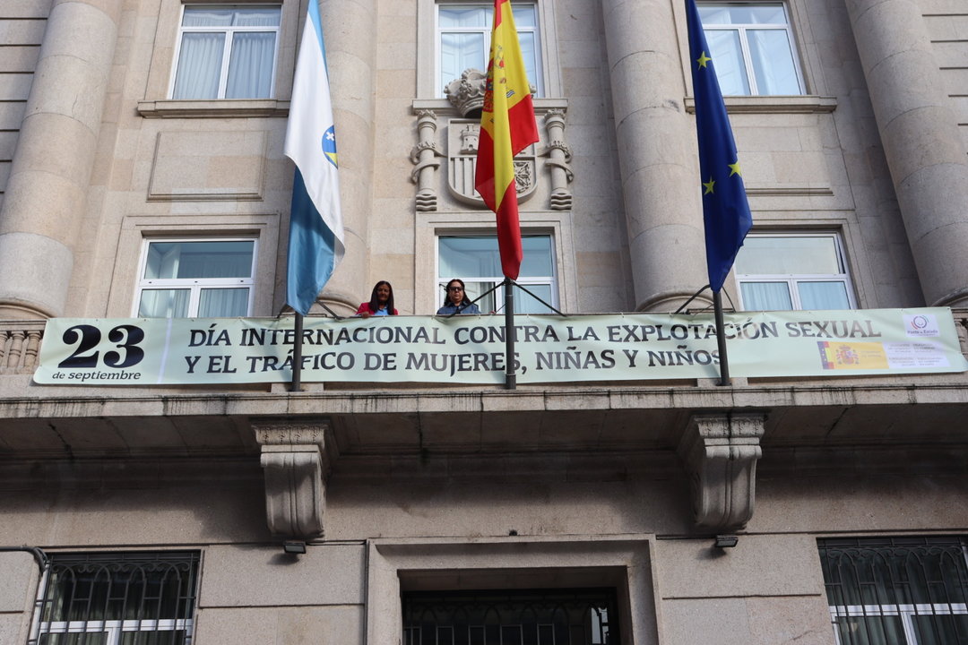 Isabel Rodríguez y María Luisa Castro, tras una pancarta de la campaña A explotación é violencia